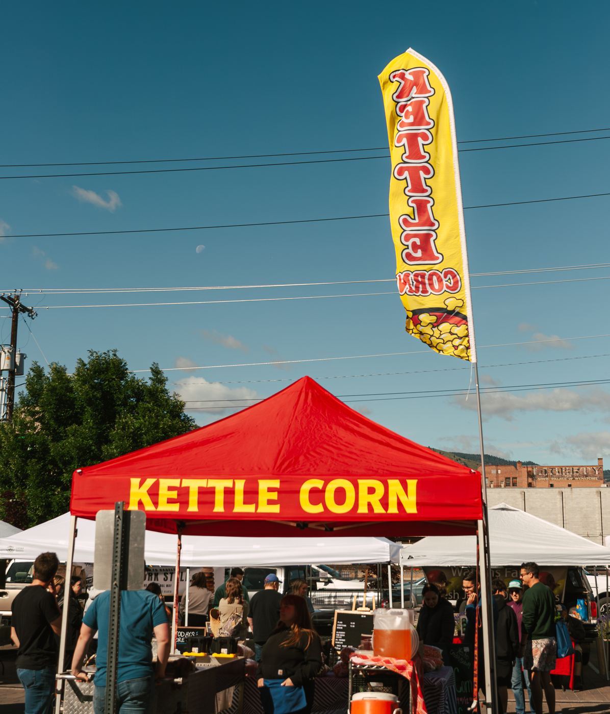 The red Kettle Corn tent and yellow flag at the farmers market