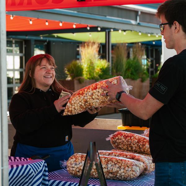 Handing a bag of kettle corn to a customer